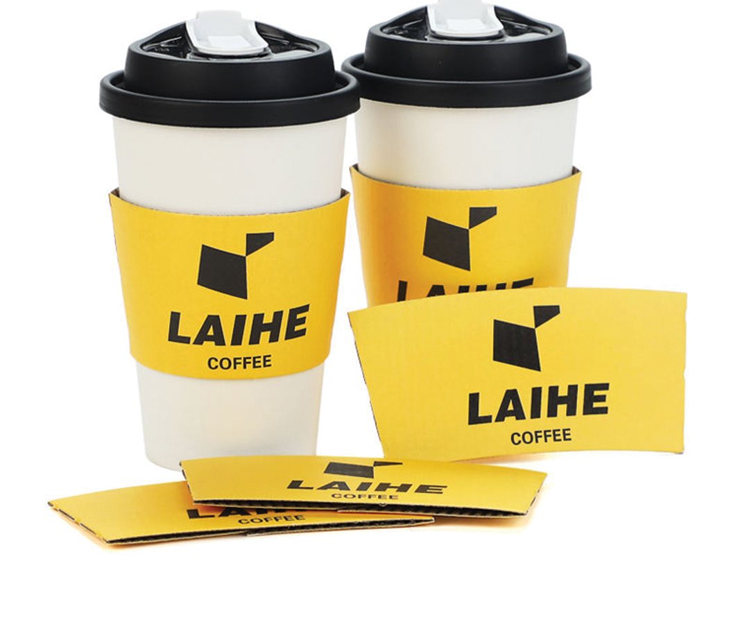Yellow branded beverage sleeves stacked beside two takeaway cups