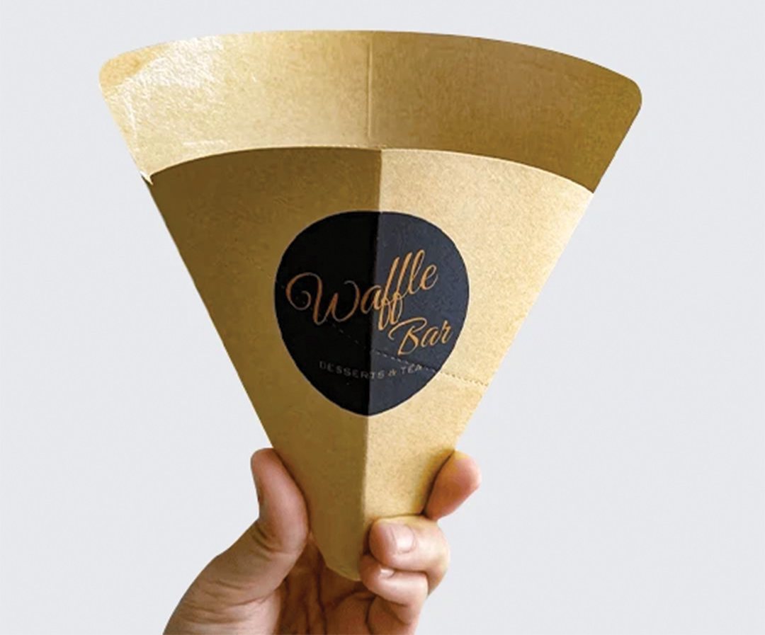 Gold crepe sleeve with a black circular logo held in one hand