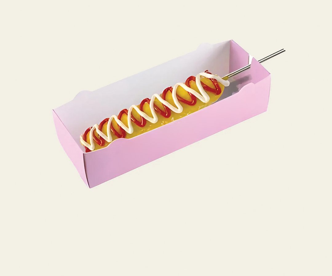 Pink printed holder supporting a corn dog on a stick