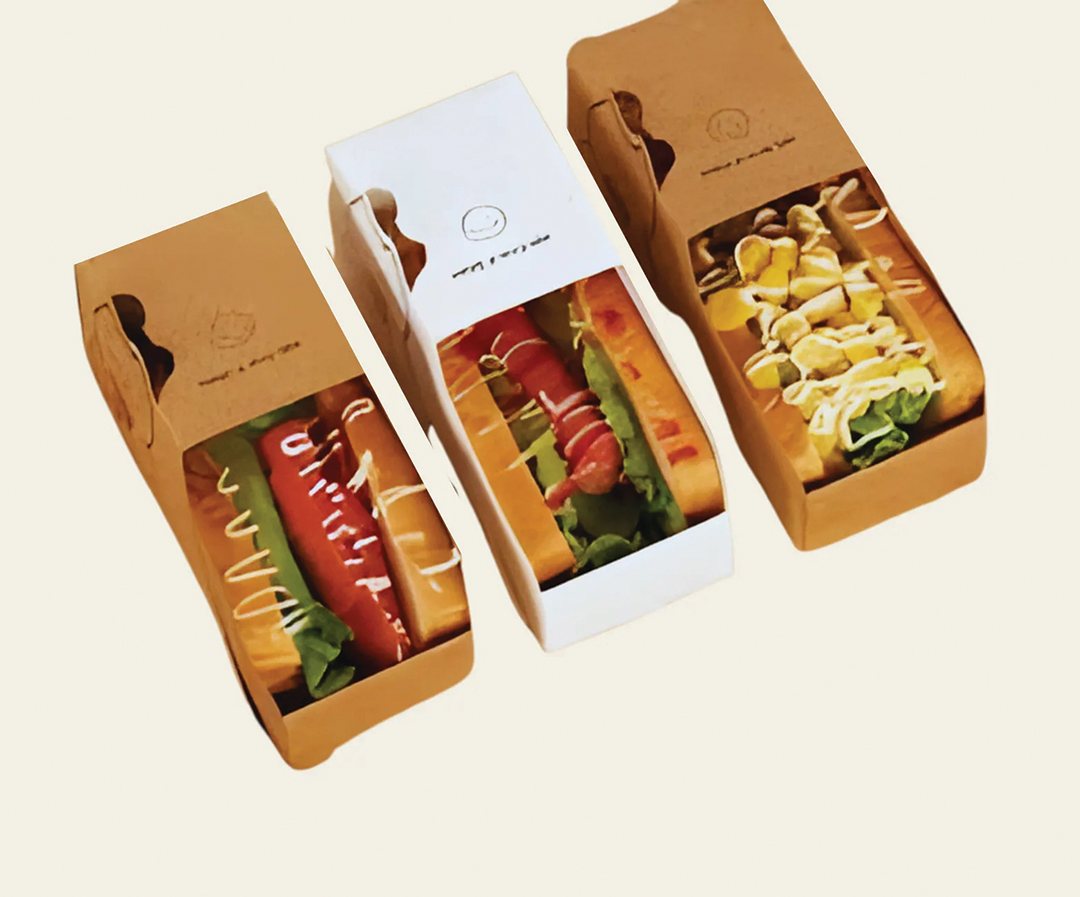 Three kraft hot dog trays loaded and lined up on a counter