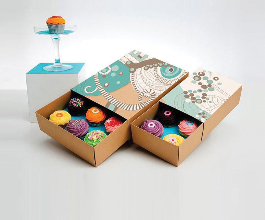 Open bakery drawer boxes holding rows of decorated cupcakes