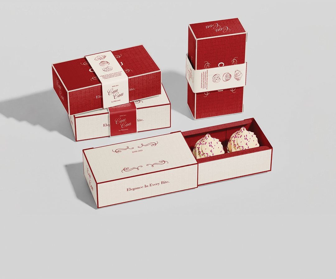 Stacked pastry sleeve boxes in cream and red beside a filled tray