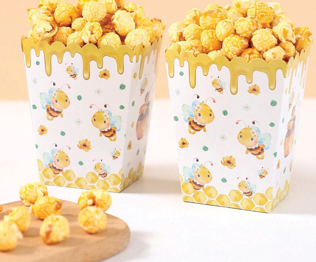 Two printed popcorn tubs filled with caramel corn on a wooden board