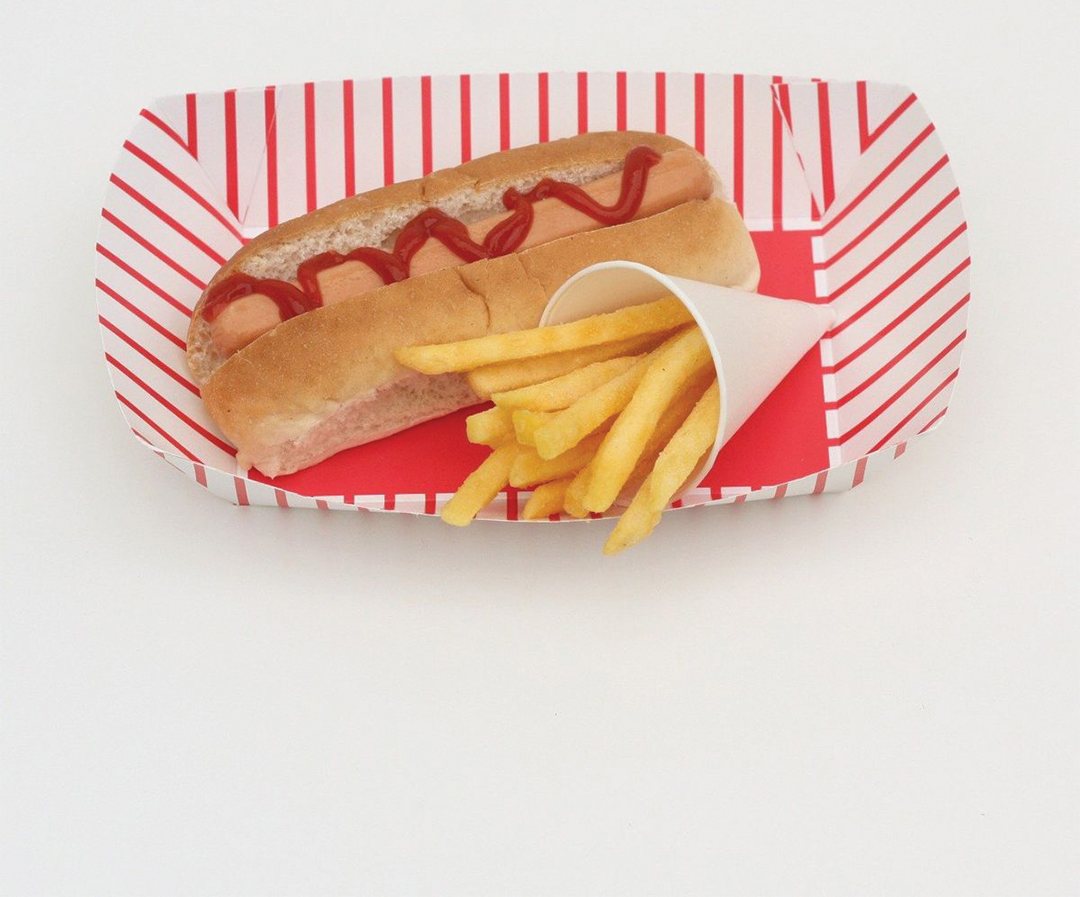 Red and white striped tray serving a hot dog alongside fries